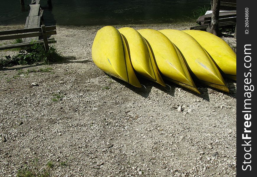 Yellow canoes in a row on the beach of a lake. Yellow canoes in a row on the beach of a lake