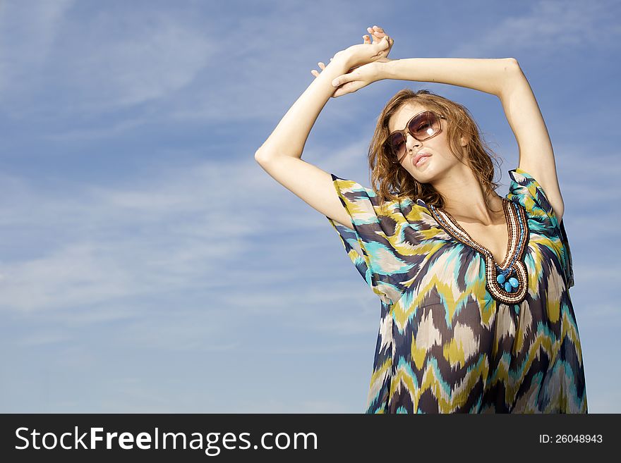 Portrait of beautiful brunette girl in sunglasses on background blue sky. Portrait of beautiful brunette girl in sunglasses on background blue sky