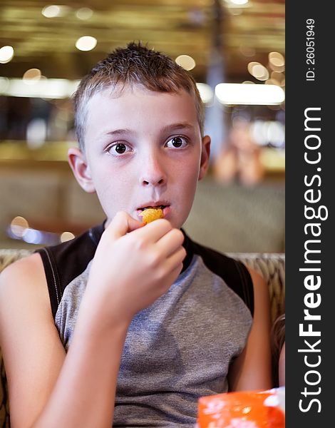 Boy eats thoughtfully  in a cafe