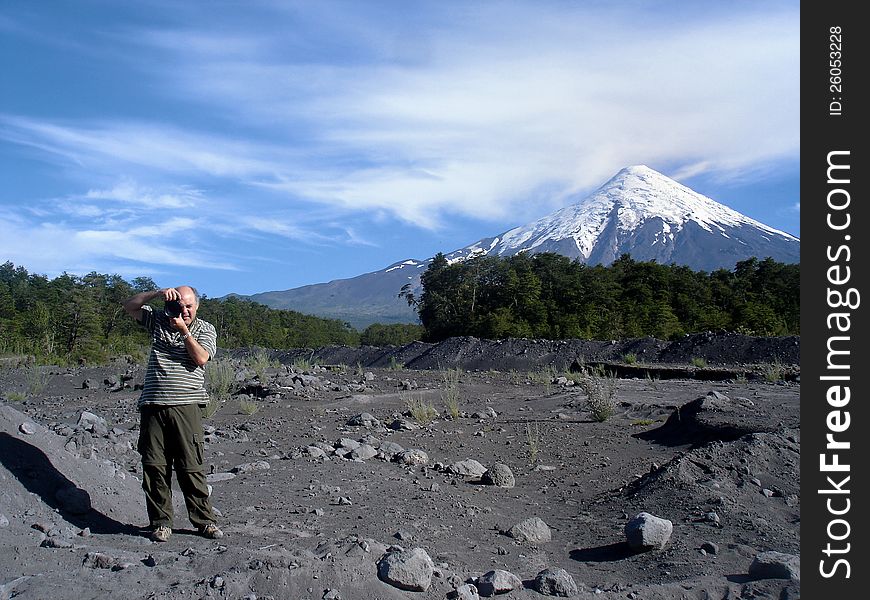 Man taking photographs at the foot of a volcano, the lava bed left by the last eruption in yna. Man taking photographs at the foot of a volcano, the lava bed left by the last eruption in yna