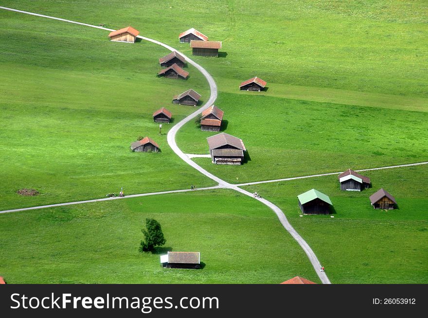 Winding road through green meadows with barn houses