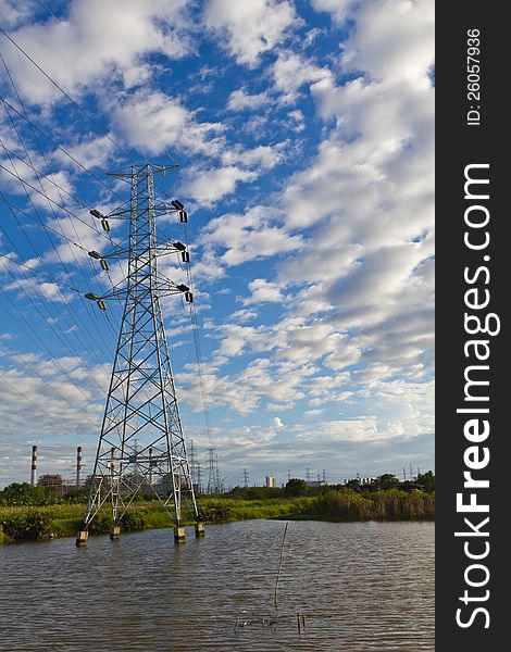 High voltage power transmission lines and pylons with gas turbine electrical power plant in background, Thailand