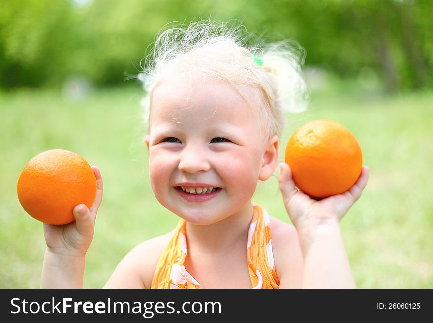 Portrait of laughing girl with oranges in the park