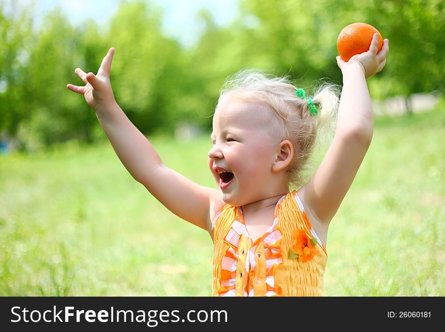 Portrait of happy girl plays with oranges in the park