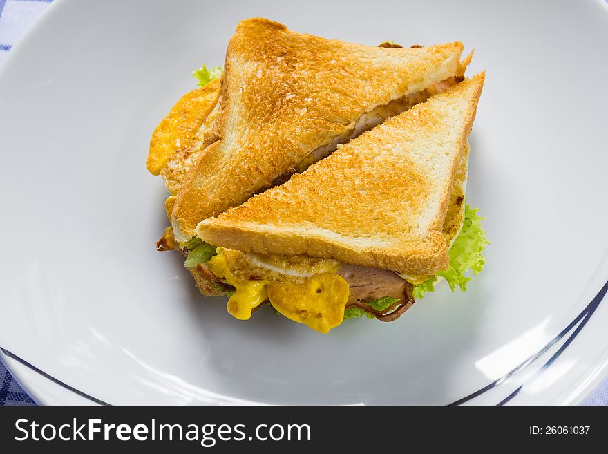 Sandwich with sliced meat loaf, cooked egg and vegetables, serving on white dish. Sandwich with sliced meat loaf, cooked egg and vegetables, serving on white dish