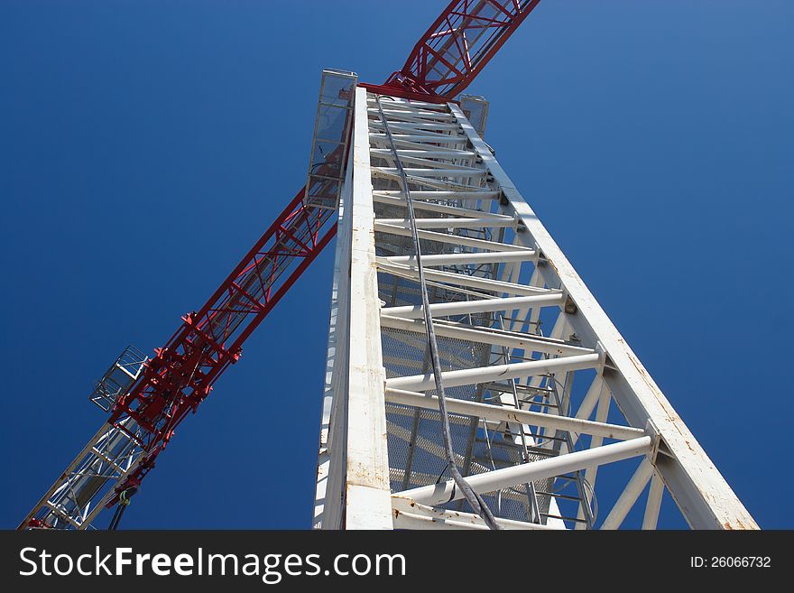 White crane with red jib against blue sky. White crane with red jib against blue sky