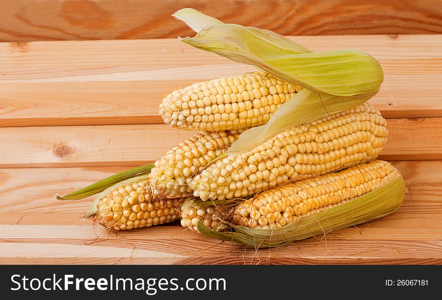 Pile of corn cobs on a wooden background. Pile of corn cobs on a wooden background