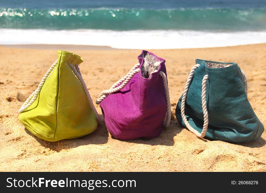 Summer holiday - three vivid bags on the seacoast, green, violet and blue