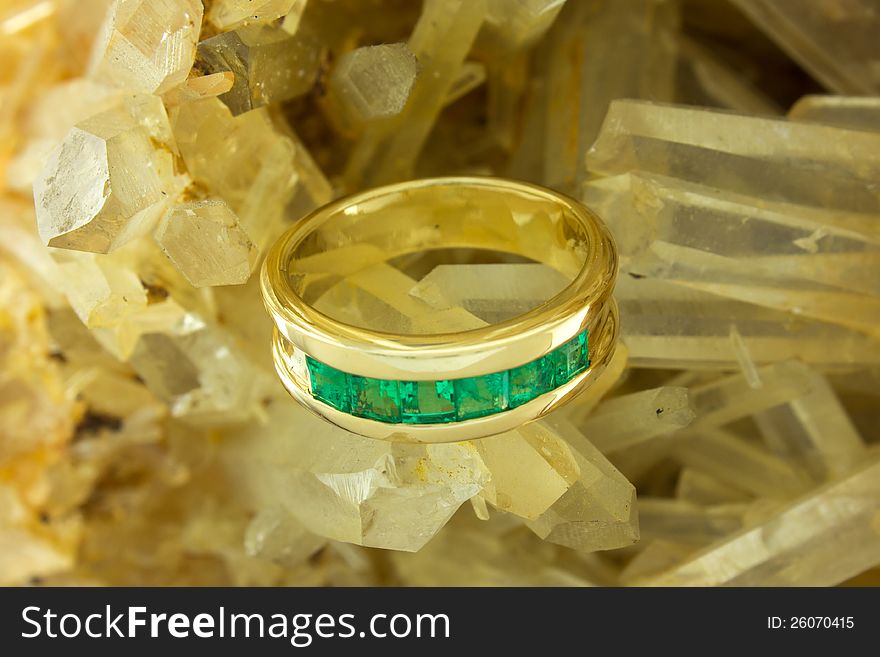 Yellow 18k gold ring with Colombian emeralds hand made in a quartz rock background. Yellow 18k gold ring with Colombian emeralds hand made in a quartz rock background.