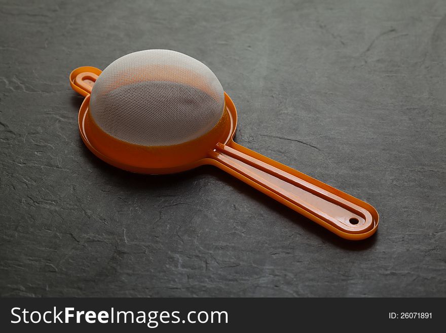 Colored plastic sieve over black background