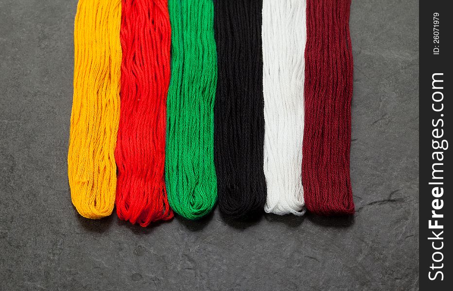 Embroidery floss laid out over black textured background. Embroidery floss laid out over black textured background