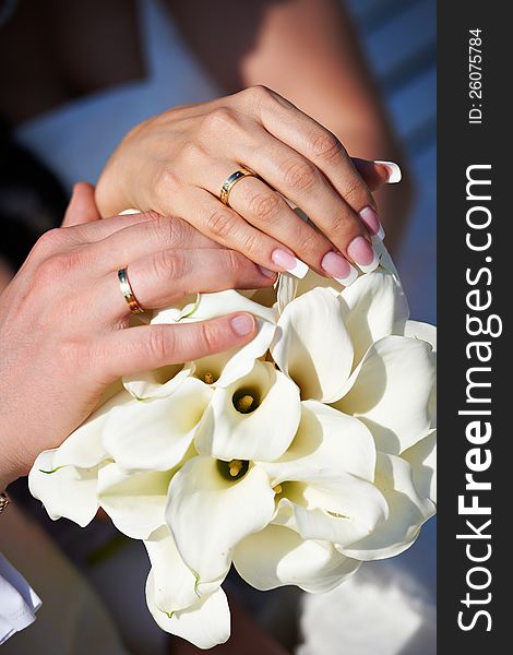 Hands with wedding gold rings happy newlyweds and bouquet of flowers kala