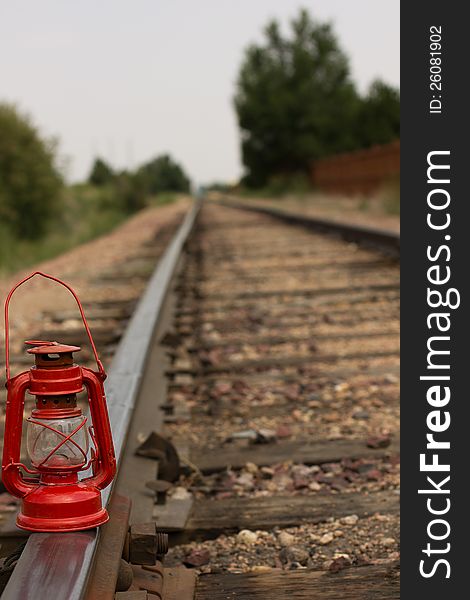 A antique red gas lantern on railroad tracks. A antique red gas lantern on railroad tracks.