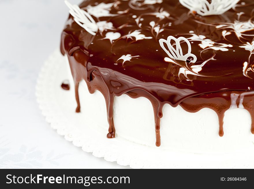 White cream cake covered by chocolate on table