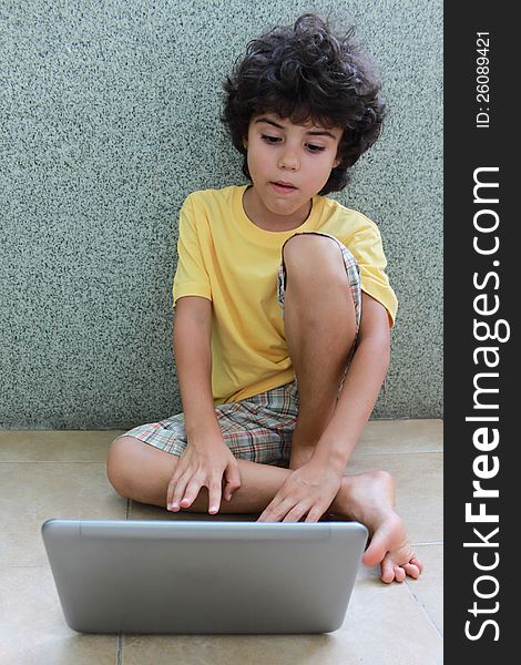 A boy sitting on the floor and working on his laptop. A boy sitting on the floor and working on his laptop