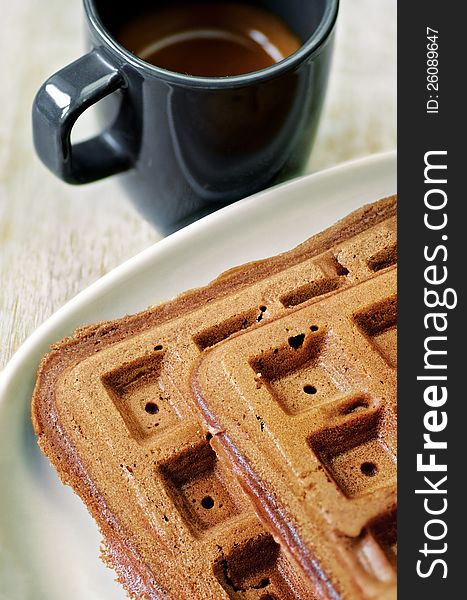 Homemade brown waffles on the plate with a cup of black coffee