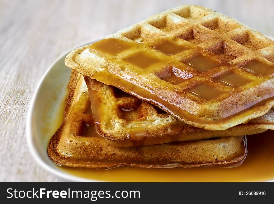 Stack of homemade waffles on the plate with sweet sauce on top