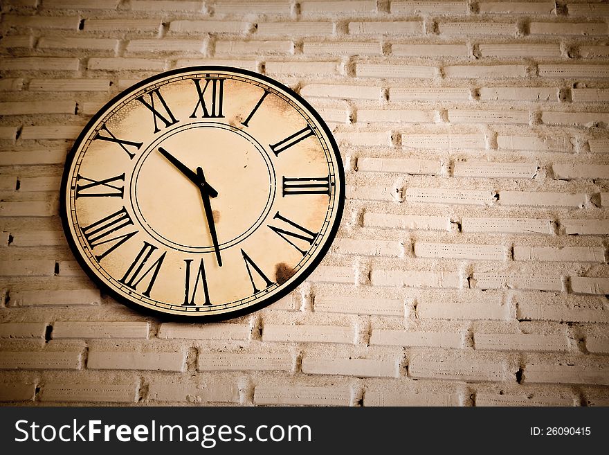 Photo vitage of Roman numeric Clock on brick wall.