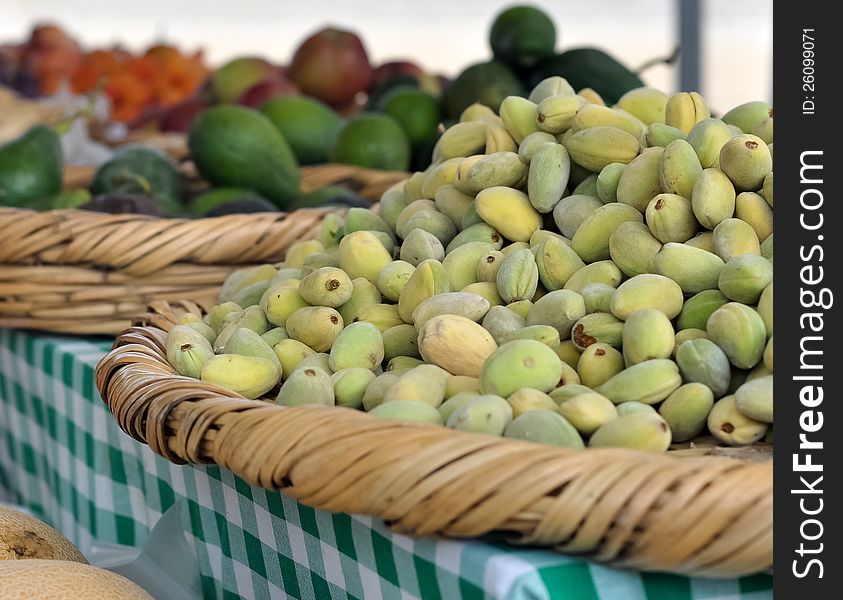 Green almonds displayed among other fruits and vegetables