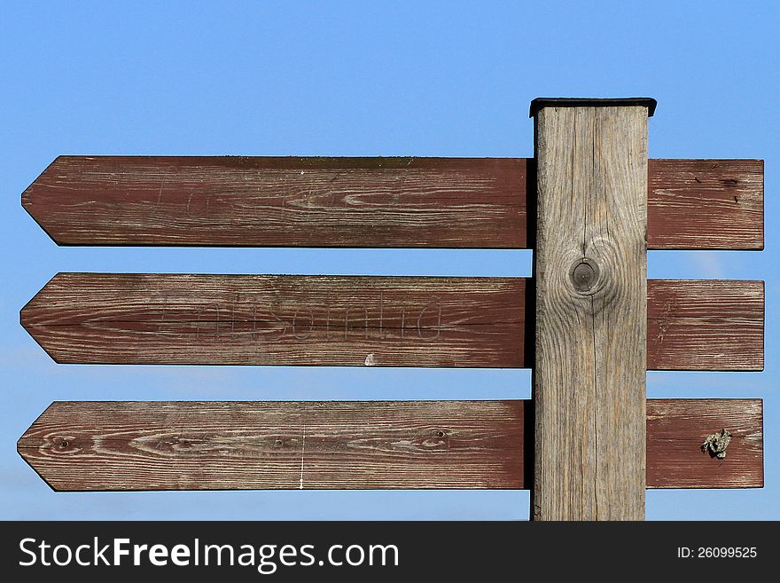 Three blank wooden arrow signs with blue sky background. Three blank wooden arrow signs with blue sky background.