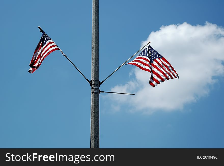 American flags on a street light pole against blue sky. American flags on a street light pole against blue sky.