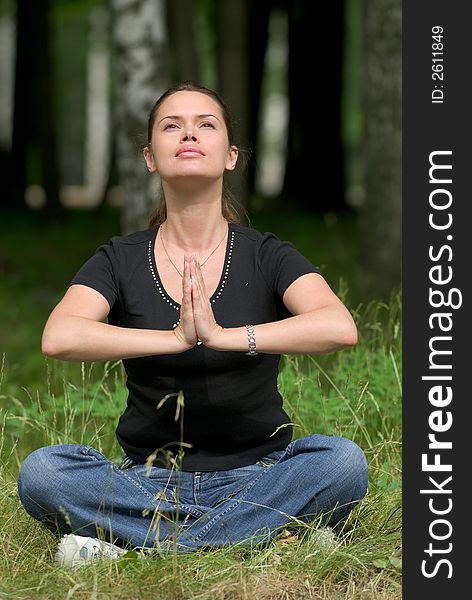 Woman doing yoga exercise on a fresh grass in a park. Woman doing yoga exercise on a fresh grass in a park