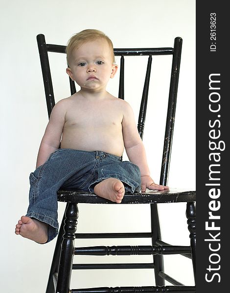 Image of a cute toddler sitting on a black chair. Image of a cute toddler sitting on a black chair