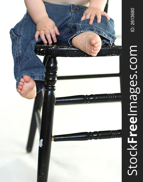 Image of a toddler sitting on a black chair, only his lower body visible. Image of a toddler sitting on a black chair, only his lower body visible