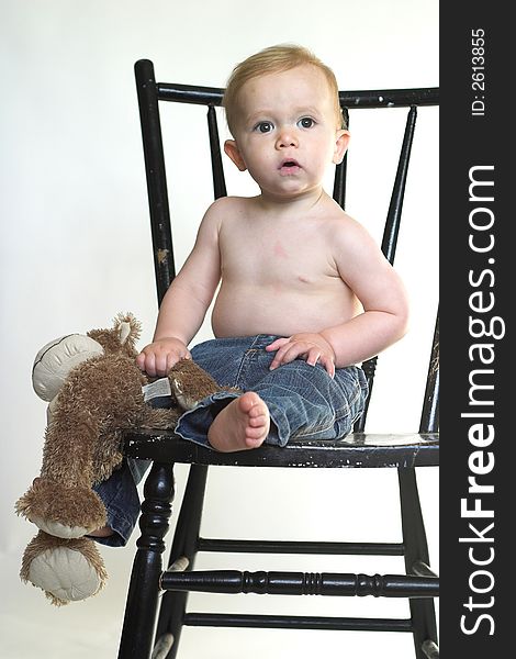 Image of a cute toddler sitting on a black chair, holding a stuffed monkey. Image of a cute toddler sitting on a black chair, holding a stuffed monkey