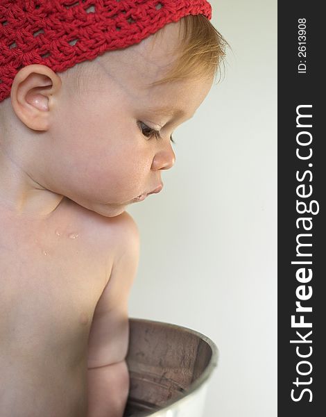 Image of cute toddler wearing a crochet cap, looking over the side of a galvanized tub