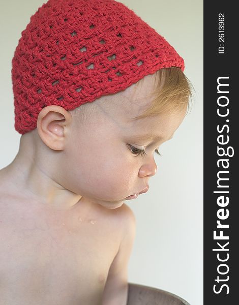 Image of cute toddler wearing a crochet cap, looking over the side of a galvanized tub