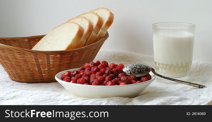 Wild strawberry, a glass of milk, and a basket of bread. Wild strawberry, a glass of milk, and a basket of bread