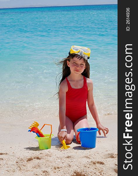 Young girl playing in the sand on the beach at a tropical island. Young girl playing in the sand on the beach at a tropical island.