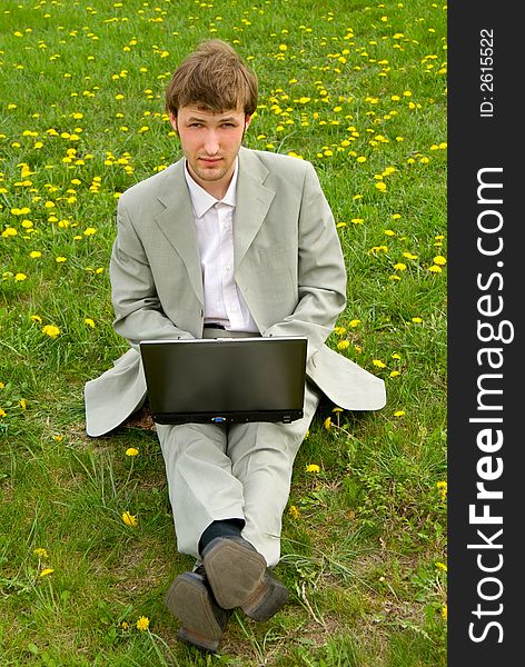 Young caucasian businessman with laptop on green grass background. Young caucasian businessman with laptop on green grass background