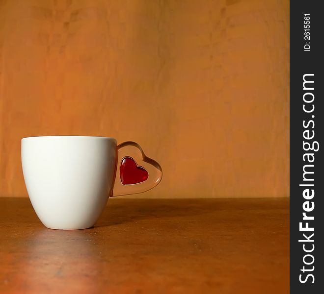 Cup with the handle in the form of heart on a wooden table
