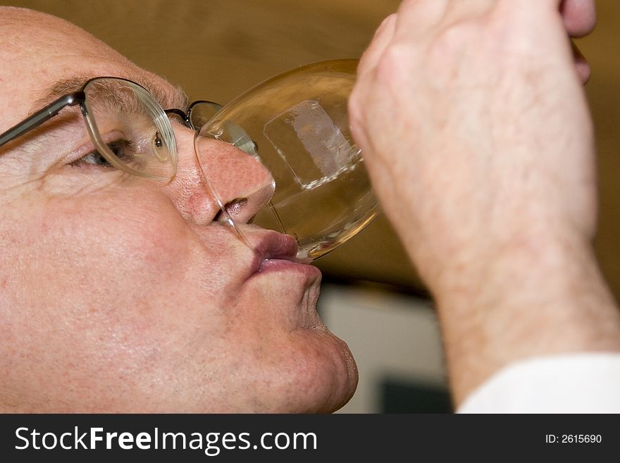 Middle-aged man tips his glass to get the last drop of wine. Sharp focus on lips and glass.