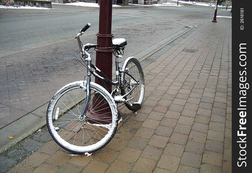 Snow covered bike leaning against a pole in Whistler Village - Creekside. Snow covered bike leaning against a pole in Whistler Village - Creekside