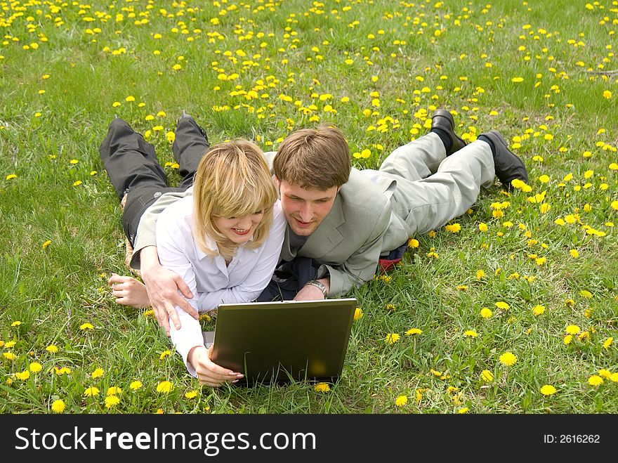 Young cheerful couple working on laptop at outdoor environment. Young cheerful couple working on laptop at outdoor environment