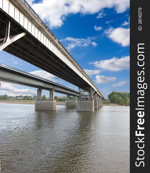 The large bridge through the river. The photo is created in the Russian province in the summer. The large bridge through the river. The photo is created in the Russian province in the summer.