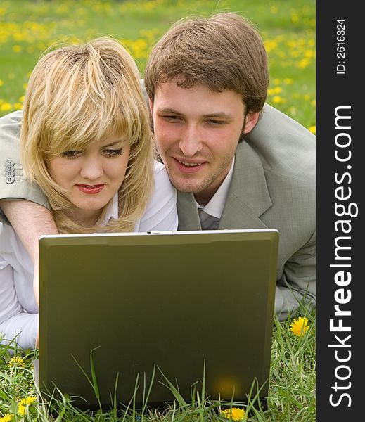 Young cheerful couple working on laptop at outdoor environment. Young cheerful couple working on laptop at outdoor environment