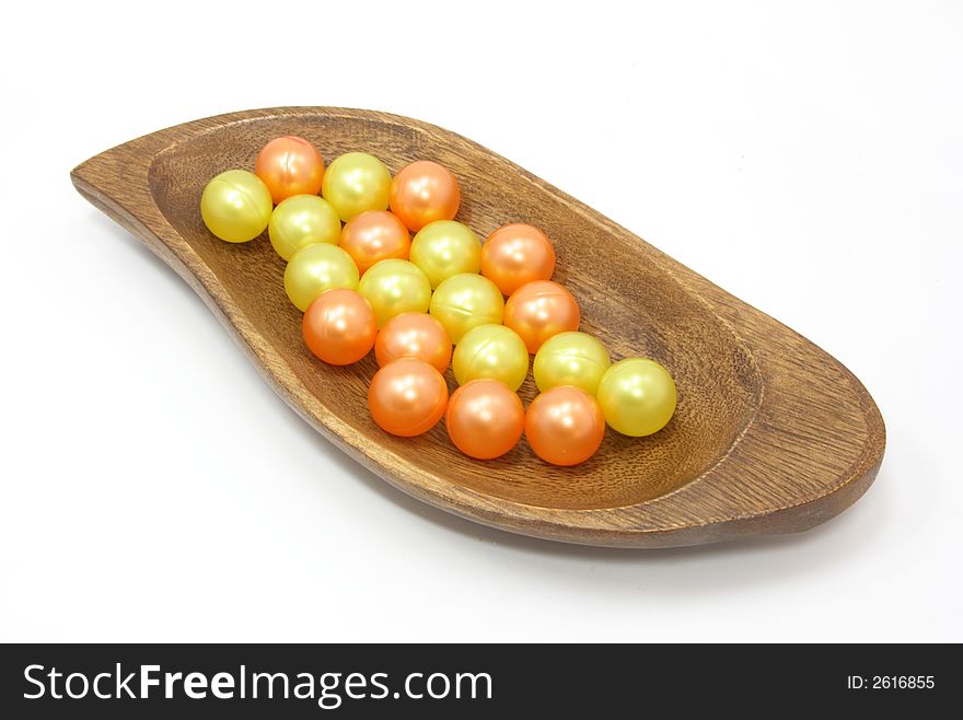 Yellow and orange bath oil pearls in wooden bowl