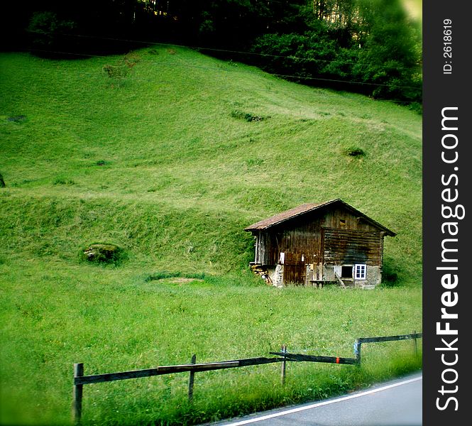 Mountain Cabin in Switzerland on a grassy hill.  Broken fence in front.