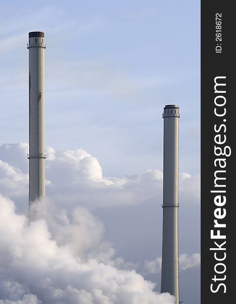 Two industrial chimneys amidst clouds