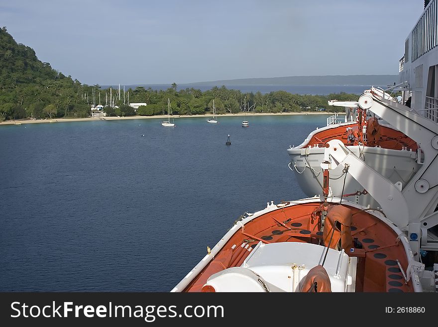 Cruise ship leaving tropical island harbor, showing lifeboats. Cruise ship leaving tropical island harbor, showing lifeboats.