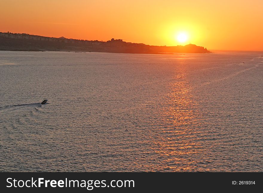 A fishing boat heading out to sea at sunrise. A fishing boat heading out to sea at sunrise