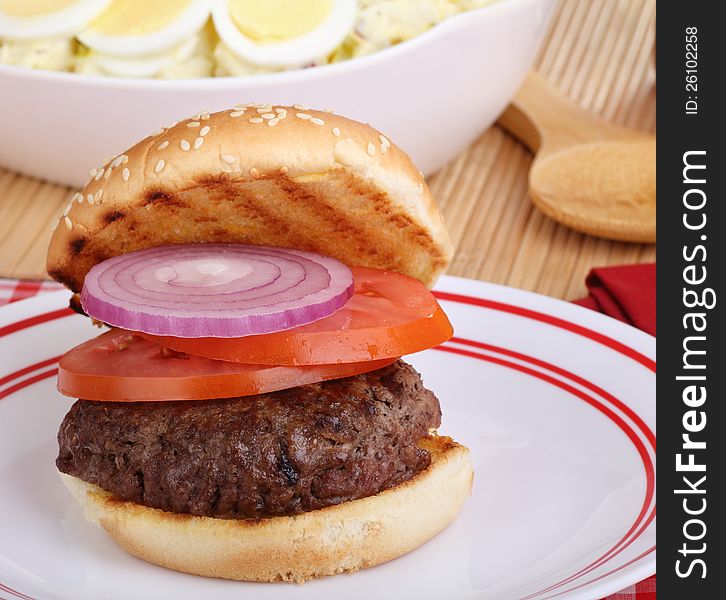 Hamburger with onion and tomato on grilled bun. Hamburger with onion and tomato on grilled bun