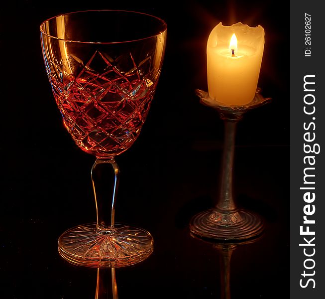 A wine glass lit by a singe candle. A wine glass lit by a singe candle