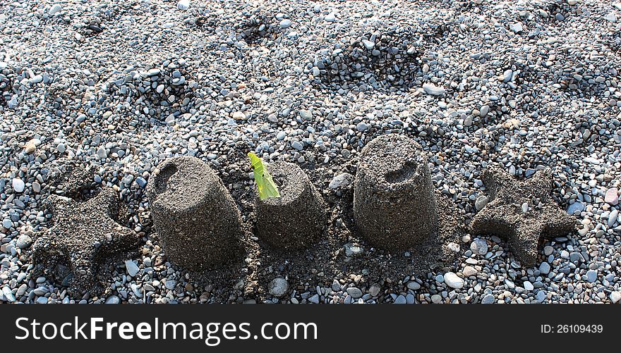 Starfish and sandpail design  with a touch of green leaves on the shoreline of a pebbled beach. Starfish and sandpail design  with a touch of green leaves on the shoreline of a pebbled beach.