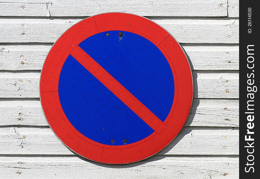 Circular no parking sign on white wooden wall.
