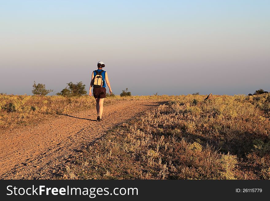 Girl goes on a mountain road at the sunset